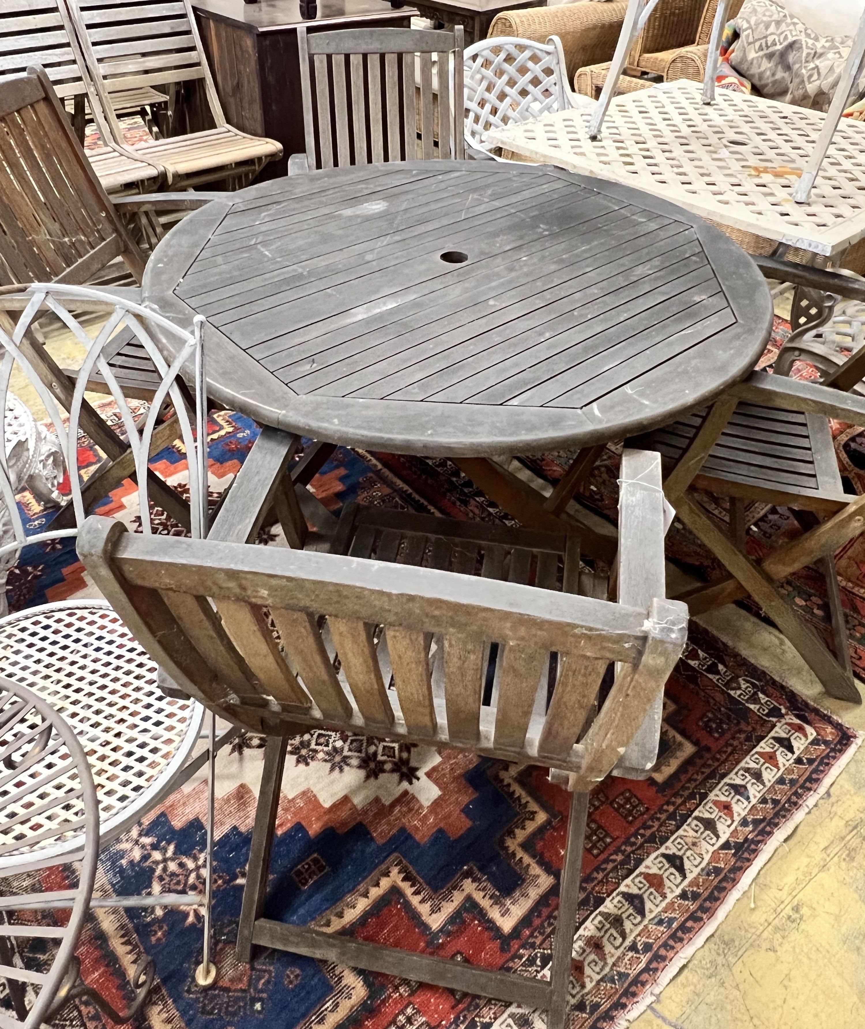 A circular weathered teak folding wooden garden table, diameter 110cm height 72cm, together with four elbow chairs
